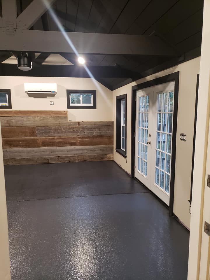 Basement with wood siding on wall and black polished floor and view of outside patio door