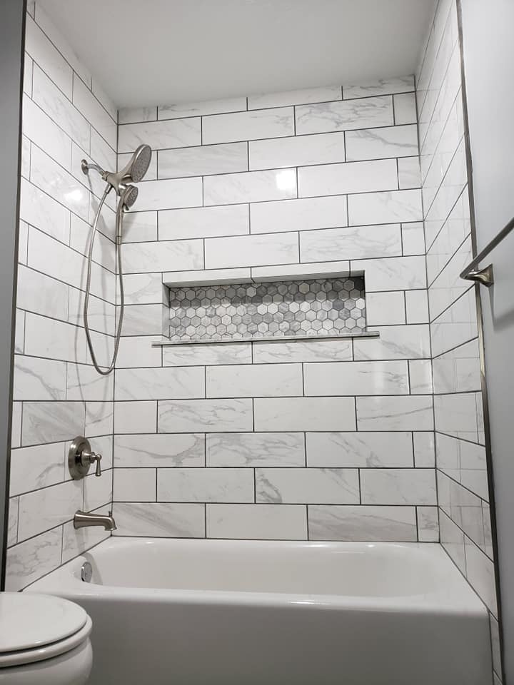 Newly remodeled shower with white and gray marble tilework